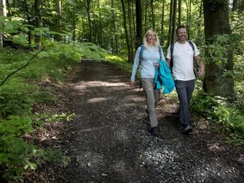 Wanderer unterwegs im Kreis Höxter Ein Paar wandert auf einem Waldweg im Kreis Höxter mit Rucksäcken und lächelndem Gesichtsausdruck.