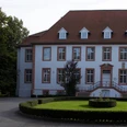Ein gepflegtes Herrenhaus mit weißer Fassade, vielen Fenstern und einem dekorativen Garten.