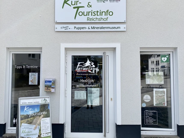Kur- und Touristinfo Reichshof Eingang der Kur- und Touristinfo Reichshof mit Prospekten und Infotafeln, helle Fassade.