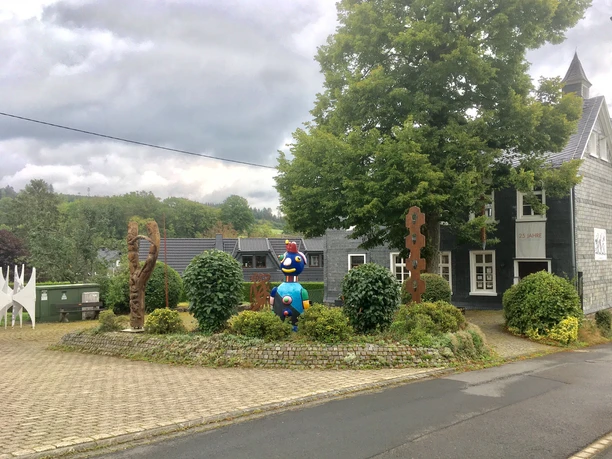 Skulpturenpark Kunst Kabinett Hespert Kunstinstallation mit bunten Skulpturen und modernem Gebäude im ländlichen Ambiente unter Wolkenhimmel.