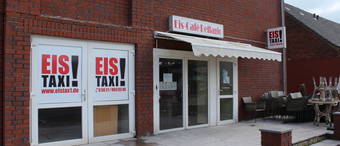 IJssalon met een rode bakstenen gevel, grote ramen en een terras met gestapelde stoelen.