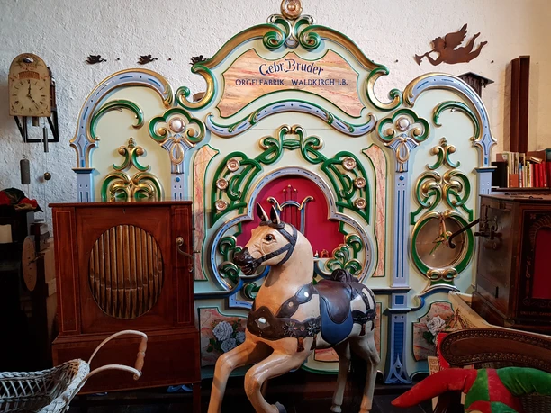 Drehorgelmuseum Antikes Karussellpferd und eine reich verzierte Orgel in einer nostalgischen Ausstellung.