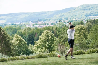 Mann spielt Golf auf dem Golfplatz mit Aussicht auf Bad Driburg.