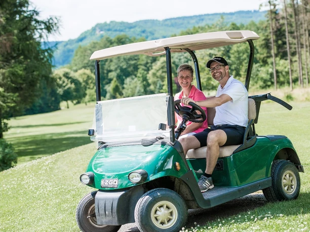 Ein Paar fährt zusammen im Golfwagen.