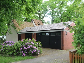 Kapelle Nordel Kapelle in waldreicher Umgebung mit blühendem Rhododendron im Vordergrund und Backsteinfassade.