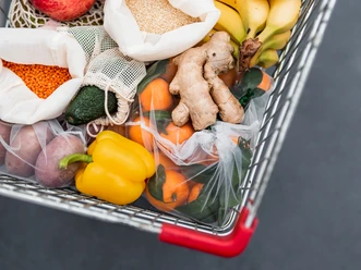 food-waste-zero-waste-shopping-in-supermarket-6RFEEZW.jpg Fruit, vegetables and grains in reusable textile fabric bags Pouch in shopping cart. Top view or flat lay. Cart with food product close up, studio shot. Food waste, zero waste shopping concept.