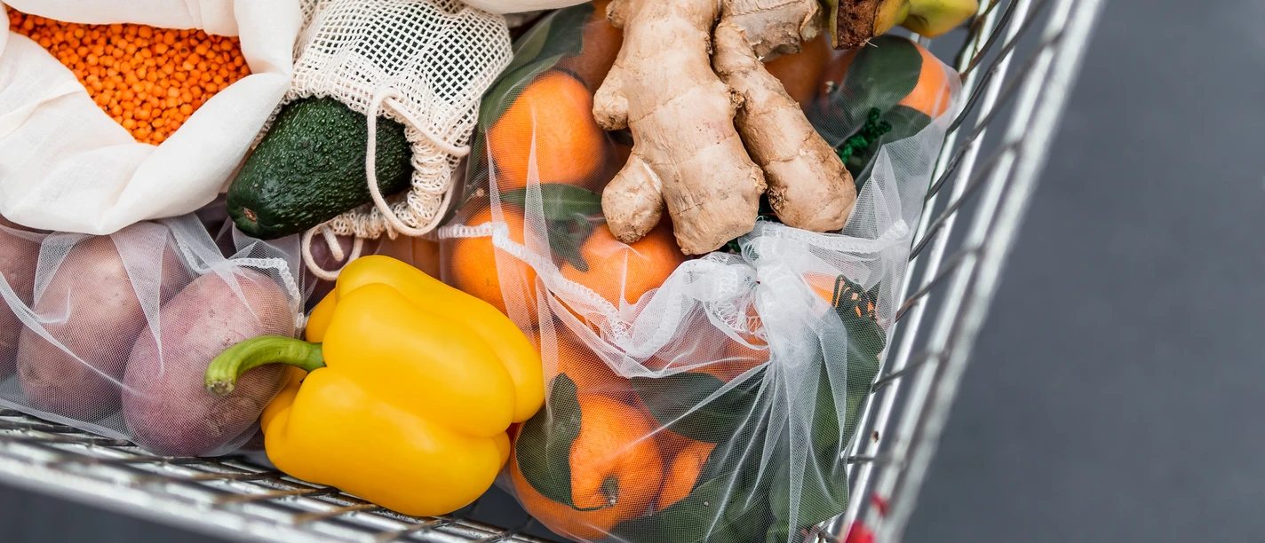 food-waste-zero-waste-shopping-in-supermarket-6RFEEZW.jpg Fruit, vegetables and grains in reusable textile fabric bags Pouch in shopping cart. Top view or flat lay. Cart with food product close up, studio shot. Food waste, zero waste shopping concept.