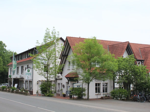 Waldhotel Moorhof Ein traditionelles Hotel mit roten Ziegeldächern und weißen Fassaden, umgeben von grünem Laub.