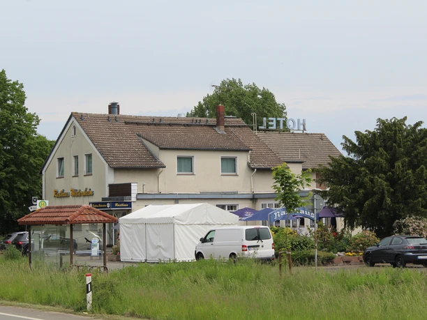 Rasthaus Wietersheim Rasthaus Wietersheim an Landstraße mit Hotelzeichen, Restaurant und parkenden Fahrzeugen.