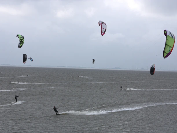 Kitesurfen Upleward Kitesurfer mit bunten Drachen gleiten bei grauem Himmel über das Wasser vor Upleward.