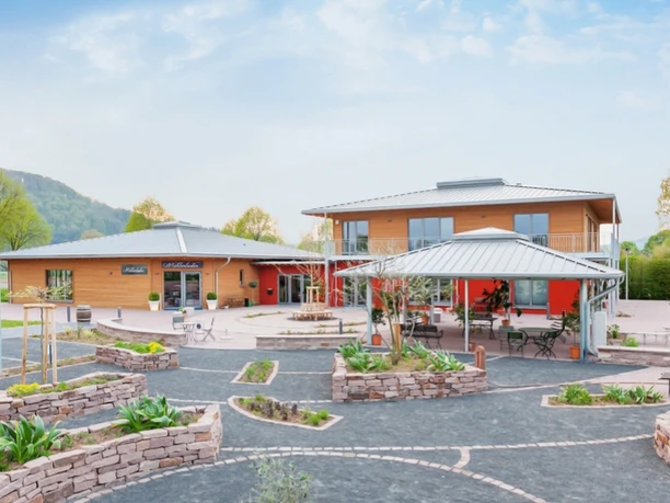 Großer, moderner Wohnmobilstellplatz mit hellen Gebäuden, gepflegten Gärten und umliegender Landschaft.