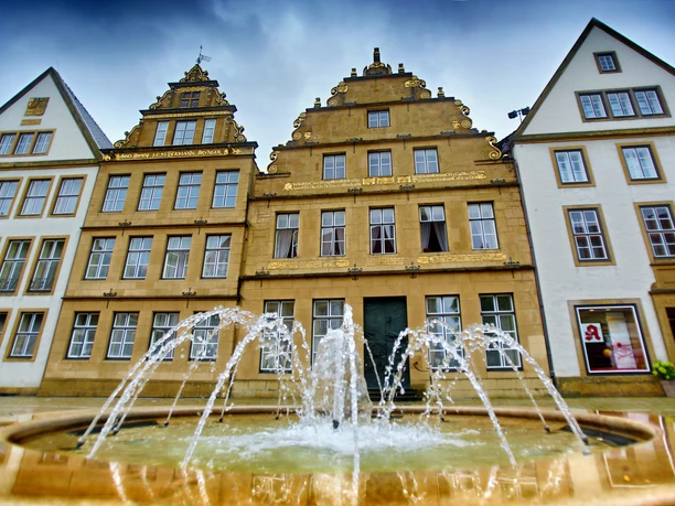 Bielefeld Alter Markt Historische Gebäude mit reich verzierten Giebeln hinter einem sprudelnden Brunnen in einem Stadtzentrum.