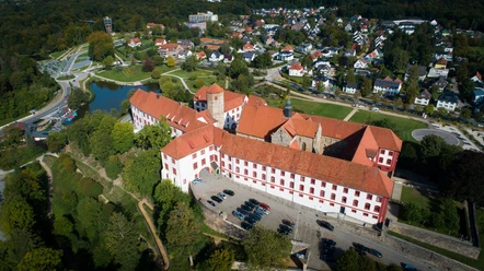 Schloss Iburg aus der Vogelperspektive Luchtfoto van een historisch kasteel met een rood dak, omringd door woongebouwen en groene ruimtes.