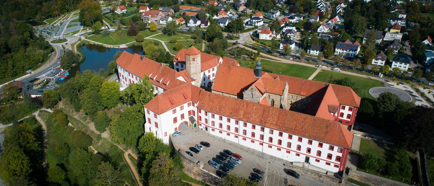 Schloss Iburg aus der Vogelperspektive Aerial view of a historic castle with a red roof, surrounded by residential buildings and green spaces.