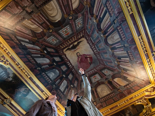 Barocker Rittersaal im Schloss Iburg Ceiling fresco in a sumptuous room, people point to a central painted figure.