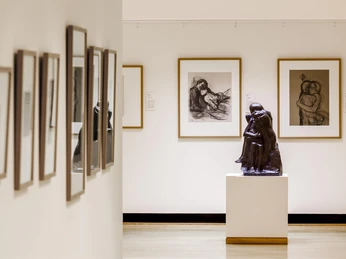 Käthe Kollwitz Museum Köln Im Käthe Kollwitz Museum in Köln ist ein Ausstellungsraum zu sehen. Im Zentrum des Raumes steht eine eindrucksvolle Skulptur, umgeben von gerahmten Zeichnungen an den Wänden.The image depicts a serene gallery space within the Käthe Kollwitz Museum in Cologne. Central to the composition, a bronze sculpture stands on a plinth, framed by expressive drawings on the walls, reflecting emotional depth and human experience associated with Kollwitz's work.