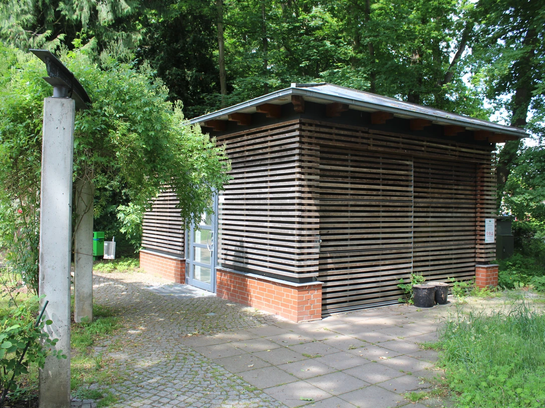 öfftl. WC im Schlosspark Etelsen Öffentliches Toilettenhäuschen im Schlosspark Etelsen mit natürlicher Holzverkleidung, umgeben von Grün.