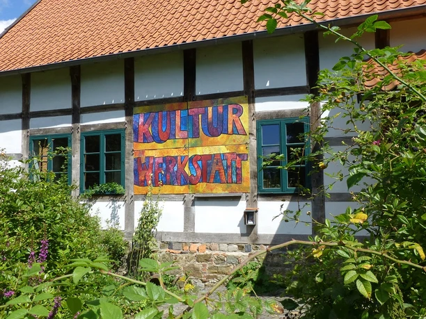 KulturWerkstatt Fachwerkhaus mit zweifarbigen Ziegeln und einem bunten Schild mit der Aufschrift "KulturWerkstatt".