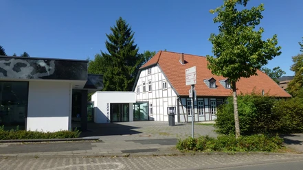 Eingang des Museums Bünde mit modernem Anbau, Fachwerkhaus und baumbestandener Umgebung.