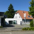 Eingang des Museums Bünde mit modernem Anbau, Fachwerkhaus und baumbestandener Umgebung.