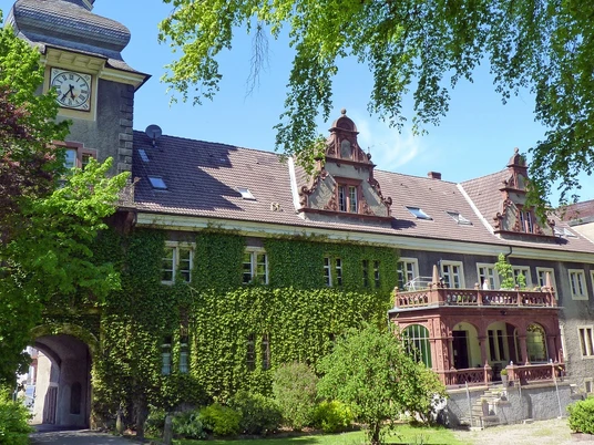 Das historische Schloß Mühlenburg mit Efeu bewachsenen Mauern und prunkvollen Giebeln bei Sonnenschein.