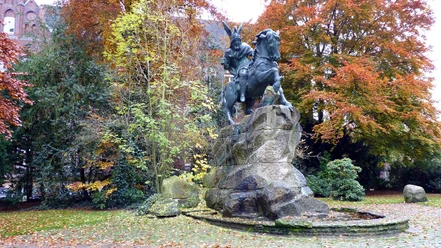 Reiterstandbild von König Wittekind auf einem Felsen, umgeben von buntem Herbstlaub in einem Park.