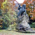 Reiterstandbild von König Wittekind auf einem Felsen, umgeben von buntem Herbstlaub in einem Park.