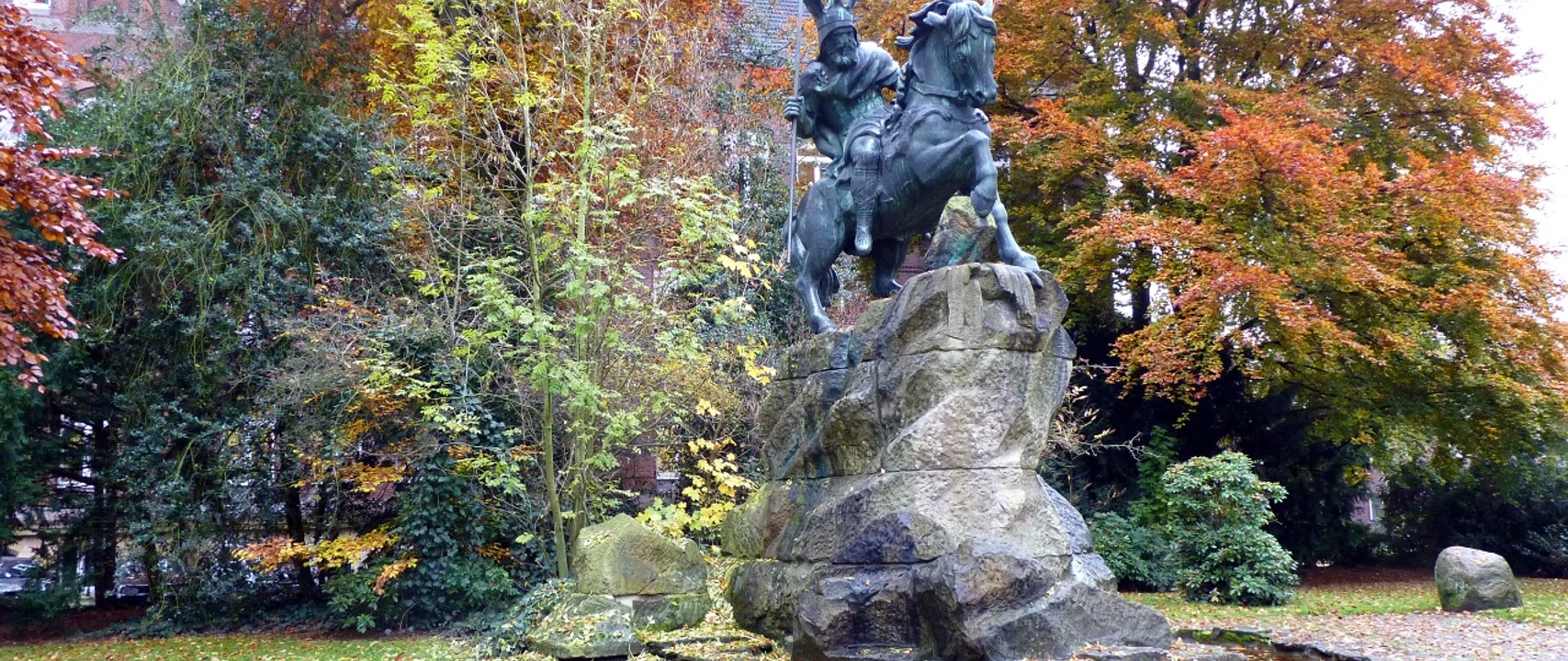 Wittekinddenkmal Reiterstandbild von König Wittekind auf einem Felsen, umgeben von buntem Herbstlaub in einem Park.