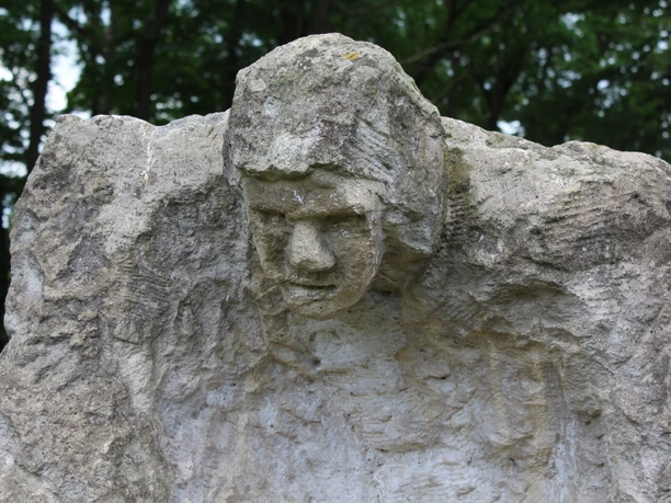 Skulpturen im Park Etelsen "Der Kärrner" Steinerne Skulptur "Der Kärrner" mit ausdrucksstarkem Gesicht inmitten von Bäumen im Park Etelsen.