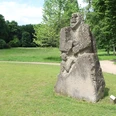 Skulptur im Park Etelsen"Kopfgeburt" Steinskulptur mit grober Struktur im Park Etelsen, zeigt menschliche Figur mit Kopf und Rumpf.