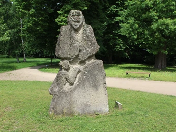 Skulptur im Park Etelsen"Kopfgeburt" Skulptur "Kopfgeburt" aus Stein auf Rasenfläche im Park Etelsen, umgeben von üppigem Grün.