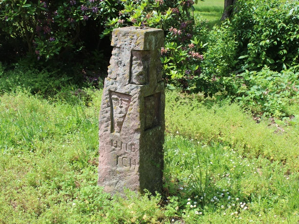 Skulptur im Park Etelsen "und ich war auch hier" Steinmonument inmitten von grüner Vegetation mit der Inschrift "und ich war auch hier".