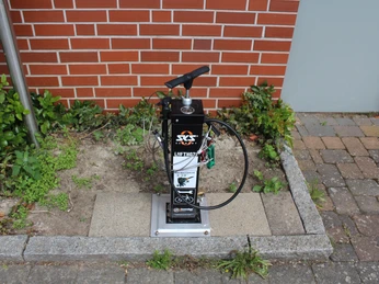 Lufttankstelle Asendorf Fahrradluftpumpstation vor rotem Ziegelgebäude auf Steinplatte, mit Schläuchen und Manometer ausgestattet.