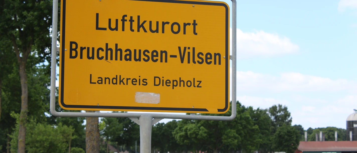 Ortsschild Town sign for the climatic health resort of Bruchhausen-Vilsen in the district of Diepholz, surrounded by green trees.