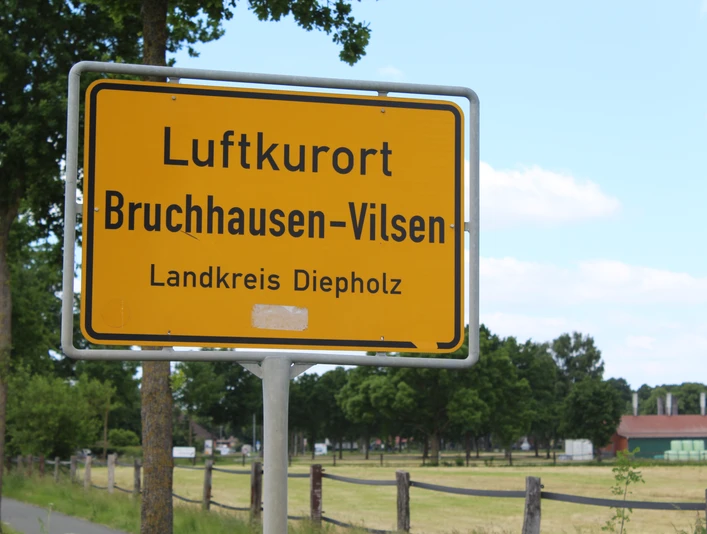 Ortsschild Ortsschild für den Luftkurort Bruchhausen-Vilsen im Landkreis Diepholz, umgeben von grünen Bäumen.Town sign for the climatic health resort of Bruchhausen-Vilsen in the district of Diepholz, surrounded by green trees.Byskilt for det klimatiske kursted Bruchhausen-Vilsen i distriktet Diepholz, omgivet af grønne træer.Plaatsnaambord voor het luchtkuuroord Bruchhausen-Vilsen in het district Diepholz, omgeven door groene bomen.