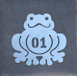Poggenpad.jpg Metalen plaatje met een lachende kikker en het nummer 01 op een grijze achtergrond.