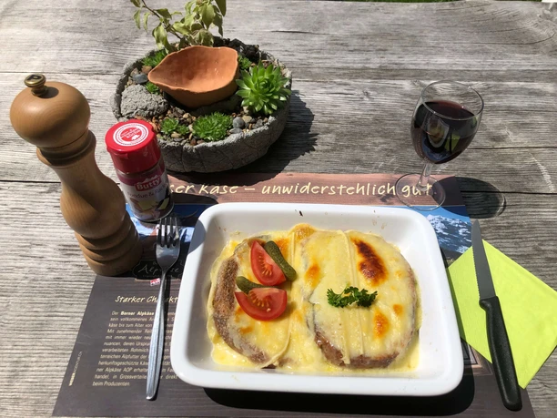 «Käseschnitte» pain avec fromage fondue Croûte au fromage avec cornichons et tomates sur assiette, table rustiquement décorée
