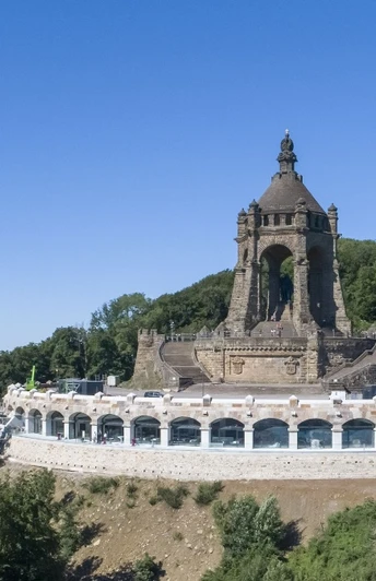 Kaiser-Wilhelm-Denkmal Kaiser-Wilhelm-Denkmal auf Hügel, umgeben von Wald, mit Aussicht auf Landschaft unter blauem Himmel.