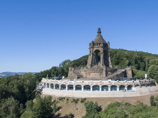 Kaiser-Wilhelm-Denkmal Kaiser-Wilhelm-Denkmal auf Hügel, umgeben von Wald, mit Aussicht auf Landschaft unter blauem Himmel.