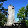 Aussichtsturm Derschlag Alter steinerner Aussichtsturm im Wald bei sonnigem Wetter, umgeben von grünen Bäumen und blauem Himmel.