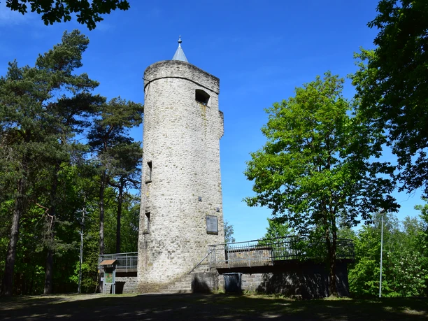 Aussichtsturm Derschlag Alter steinerner Aussichtsturm im Wald bei sonnigem Wetter, umgeben von grünen Bäumen und blauem Himmel.