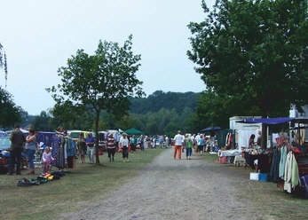 Mardorf Trödelmarkt Der Trödelmarkt in Mardorf zeigt Händler und Besucher entlang eines Schotterwegs mit bunten Ständen.