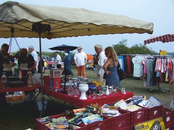 Mardorf Trödelmarkt Ein Flohmarkt in Mardorf mit Menschen, die an Ständen mit Glaswaren und Kleidung stöbern.