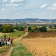 Wandern in den Weserdörfern Eine Gruppe wandert auf einem ländlichen Weg mit Blick auf Hügel und ein weitläufiges Tal.