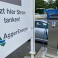 Ladesäule in Wildbergerhütte.JPG Eine moderne E-Ladesäule von AggerEnergie, neben einem Auto auf einem Parkplatz mit grüner Umgebung.