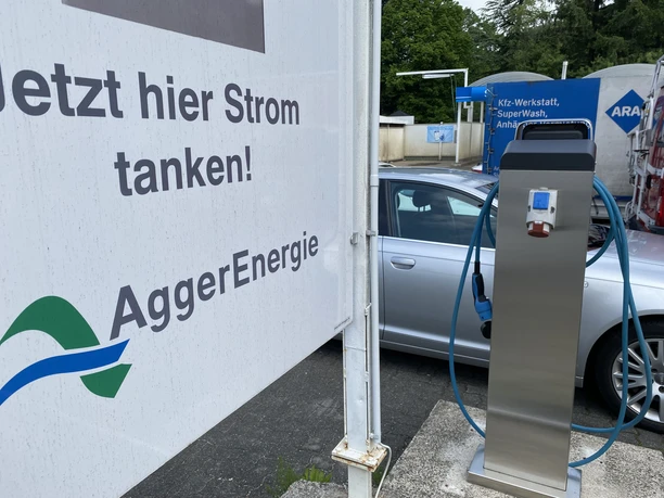 Ladesäule in Wildbergerhütte.JPG Eine moderne E-Ladesäule von AggerEnergie, neben einem Auto auf einem Parkplatz mit grüner Umgebung.