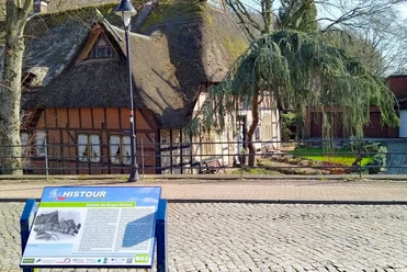 Ostseite des Burger Marktes Reetdachhaus mit Infotafel am Markt