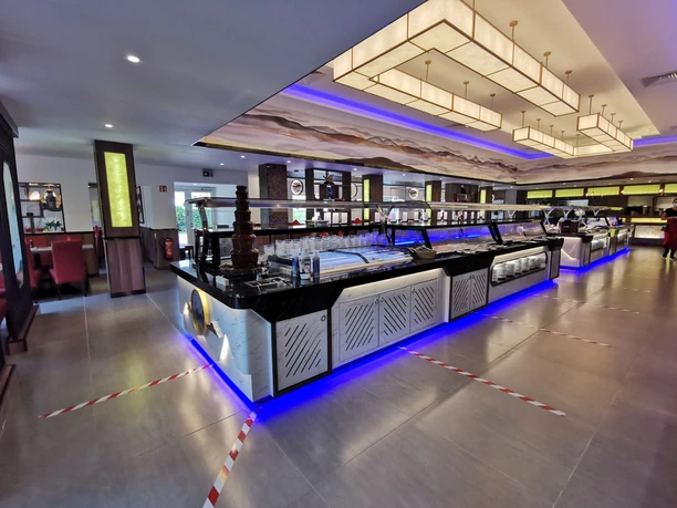 Asia-Restaurant Fang Buffetbereich in einem asiatischen Restaurant mit beleuchtetem Tresen, Schokoladenbrunnen und modernen Deckenleuchten