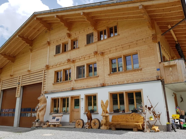 Holzchalet mit geschnitzten Holzskulpturen davor