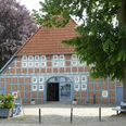 Clüverhaus Historisches Fachwerkhaus mit blauen Fensterläden und rotem Ziegeldach unter grünen Bäumen.